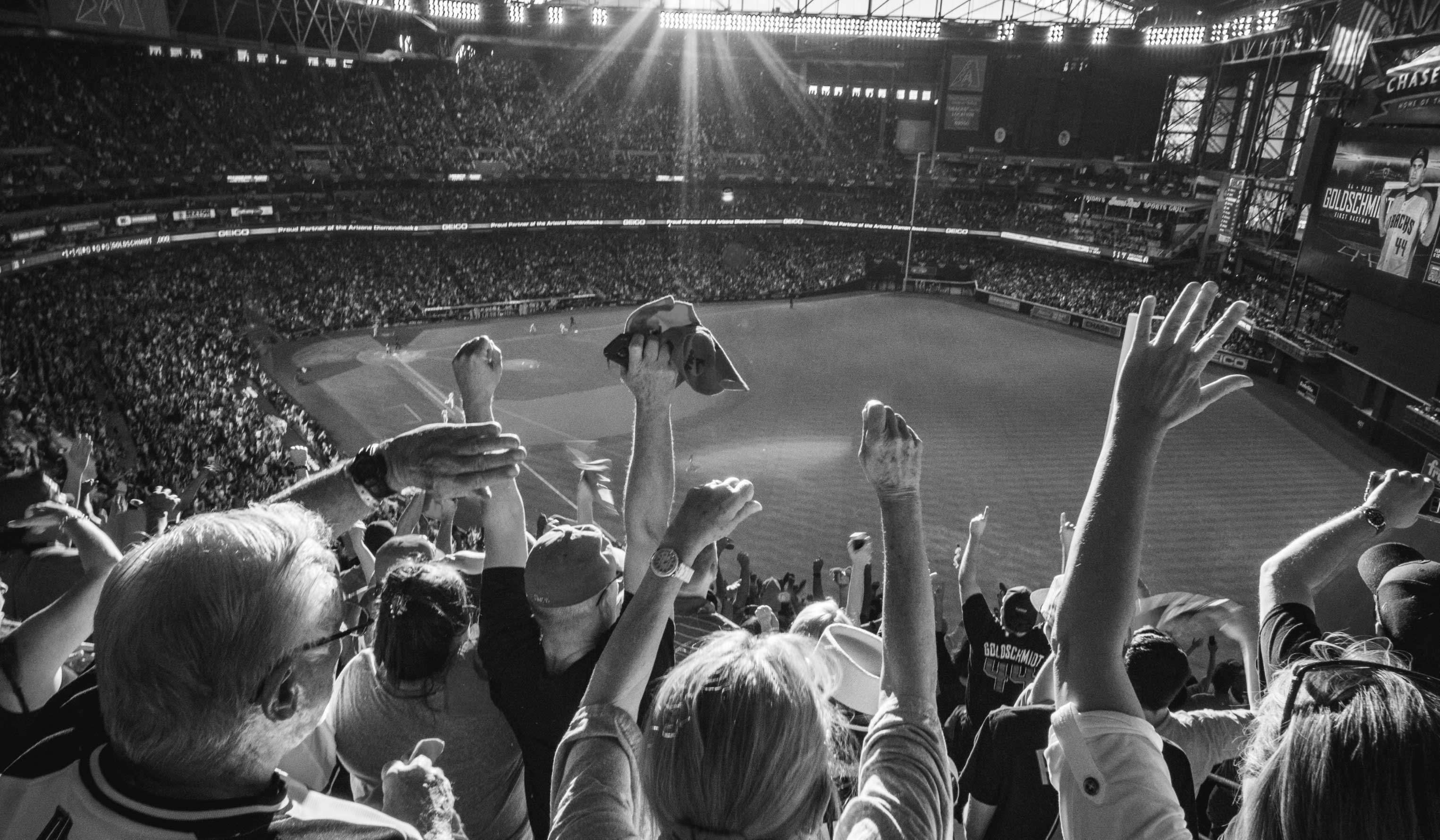 A crowd of people cheer at a baseball stadium